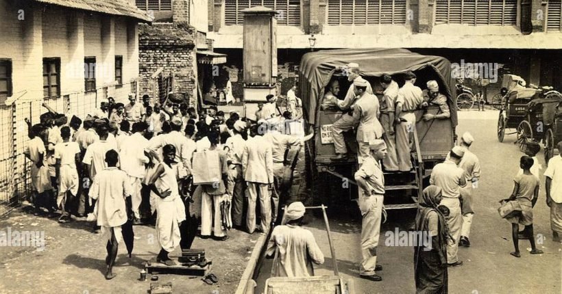 crowd-gathered-around-a-sidewalk-performer-at-a-bus-stop-in-calcutta-in-1945-W4YJW3